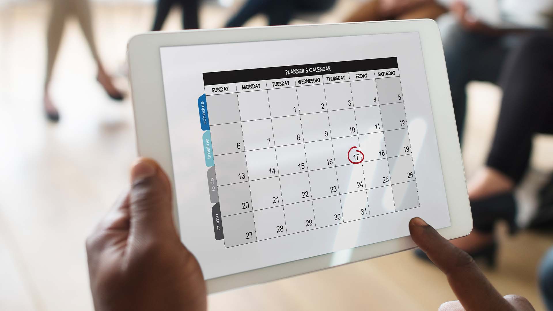 A person is holding an ipad with the calendar on it.