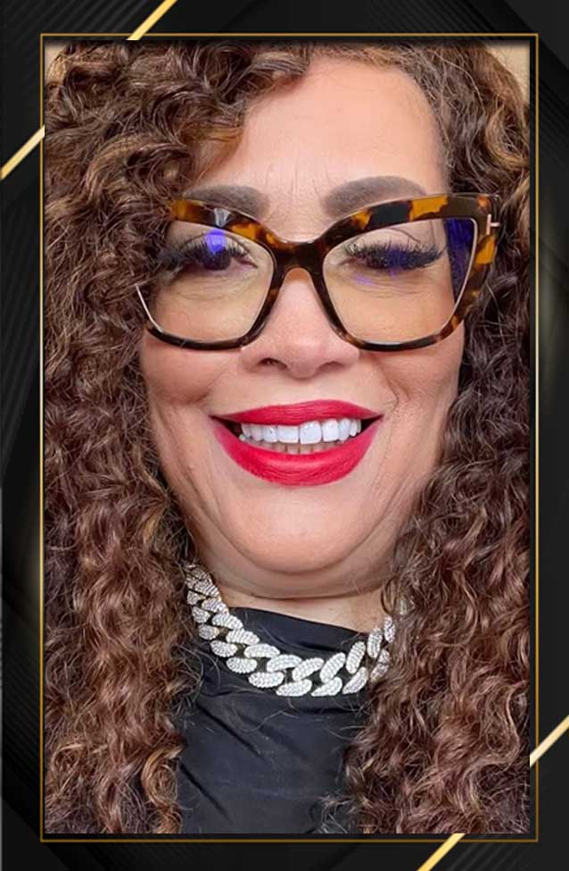 A woman with curly hair wearing glasses and smiling.
