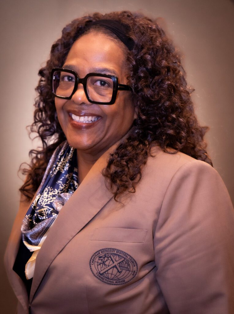 Smiling woman wearing glasses and blazer.