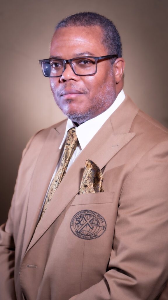 Man in brown suit and glasses.