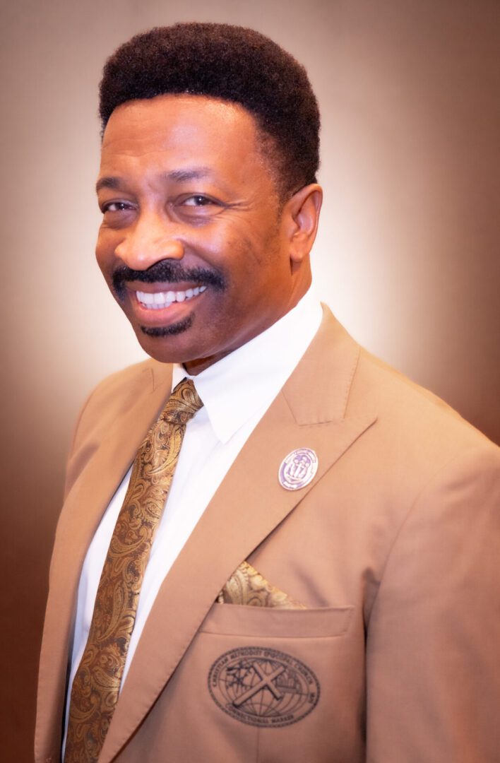 Smiling man in brown suit and tie.